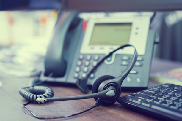 fokus auf call center kopfhörer-gerät am telefon voip-anlage am schreibtisch für hotline telemarketing-konzept mit vintage farbfilter hautnah - back office stock-fotos und bilder