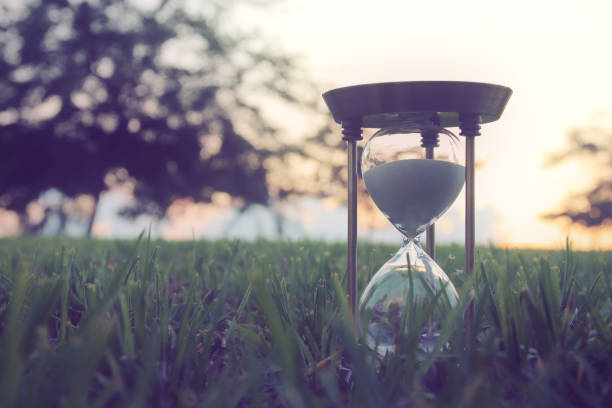 istock Hourglass in the grass time during sunset. vintage style. 1019271114