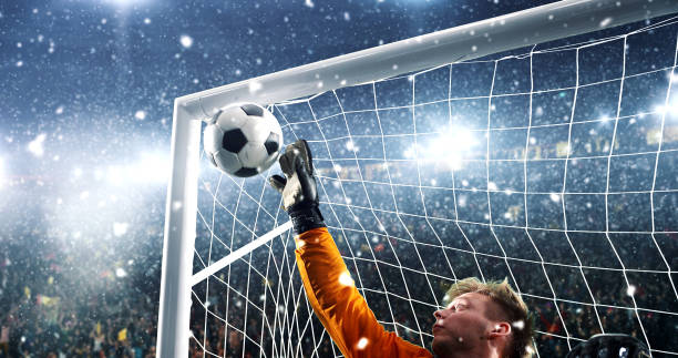 istock Goalkeeper tries to save from a goal on a professional soccer stadium while it's snowing. 1019280362
