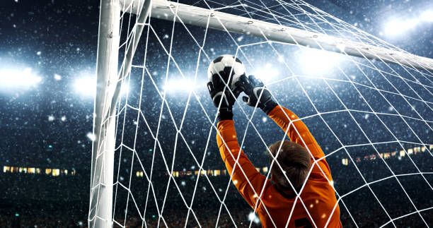 istock Goalkeeper tries to save from a goal on a professional soccer stadium while it's snowing. 1019280496