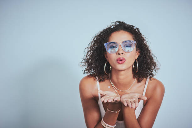 Spread the love, spread the fun and you'll be happy Studio shot of a beautiful young woman posing against a blue background blowing a kiss stock pictures, royalty-free photos & images