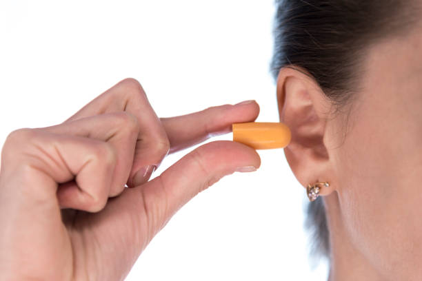 young girl holding ear plugs near the ear young girl holding ear plugs near the ear ear plug stock pictures, royalty-free photos & images