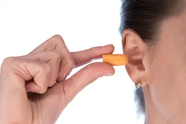 young girl holding ear plugs near the ear