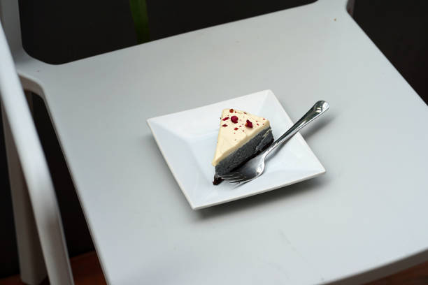 istock Charcoal cheese cake with red rose petal on white plate 1019306272