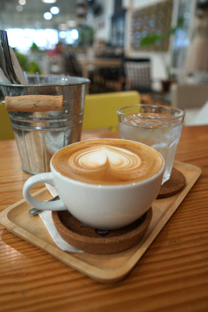 istock Heart shape latte art coffee on the timber table with iced plain water 1019306280