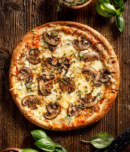 istock Mushroom pizza with addition mozzarella cheese and herbs on a wooden table 1019309836