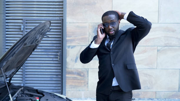 istock Businessman standing by broken car with open hood, talking over phone, breakdown 1019313106