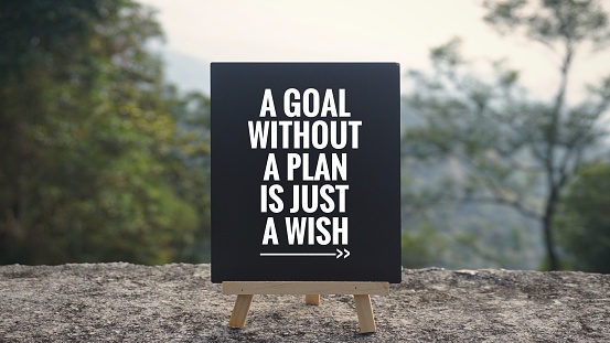 - ‘A goal without a plan is just a wish’ written on a blackboard. Blurred styled background.