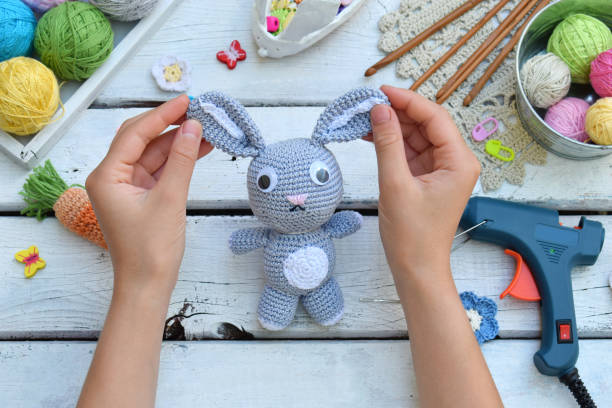 istock Making rabbit with carrot. Crochet bunny for child. On table threads, needles, hook, cotton yarn. Handmade crafts. DIY concept. Small business. Income from hobby. 1019349828