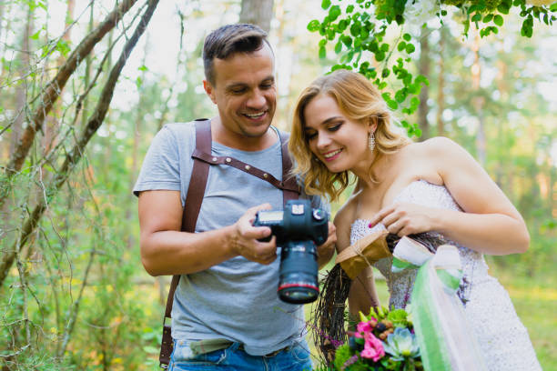 Photographer and bride watching recently taken photos stock photo