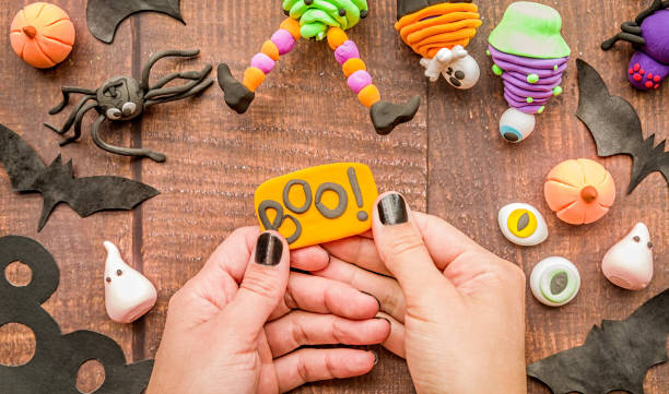 female hands with black nails making halloween cupcake craft on wooden table top view halloween concept. female hands with black nails making halloween cupcake craft top view polymer clay sweets stock pictures, royalty-free photos & images
