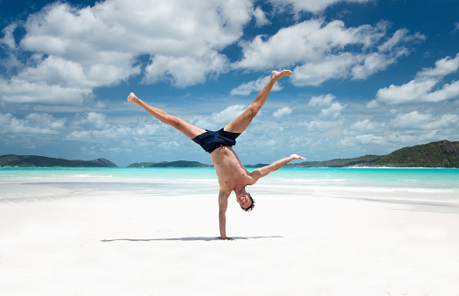 Handsome Athlete in a one handed capoeira pose enjoying this beautiful white turquoise sand beach at the famous Whitsunday Islands in Australia. Nikon D810. Converted from RAW.