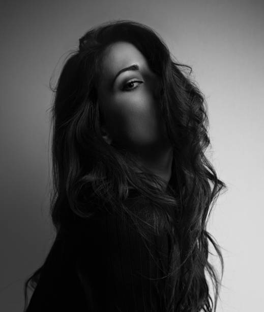 istock Thinking emotion thinking beautiful woman looking through long hair on dark background. Closeup portrait. Art. Black and white 1019362132