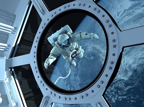Astronaut is looking at Earth through the porthole.\