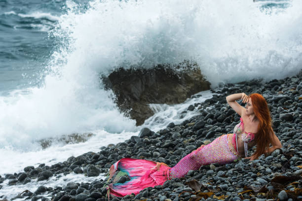 istock Beautiful mermaid with long tail on sea shore 1019372368