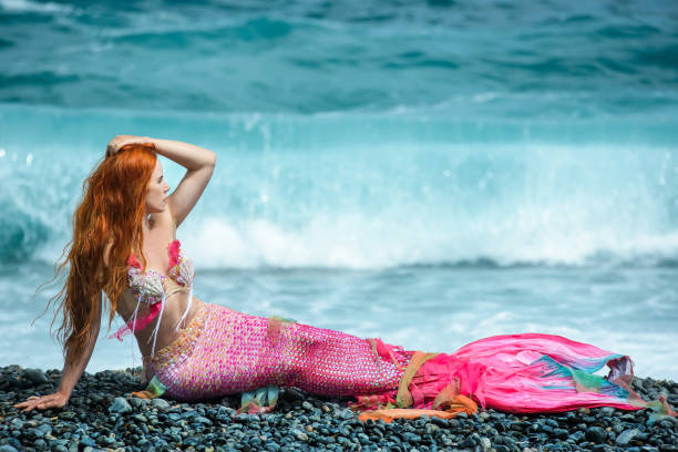 istock Beautiful mermaid with long tail on sea shore 1019372644