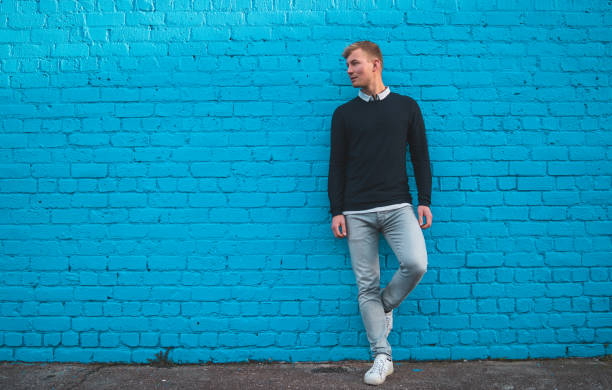 istock Young man standing in front of big teal blue wall. 1019375904