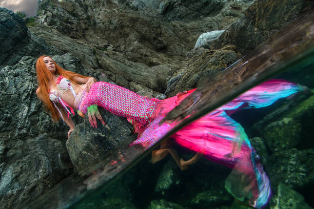 istock Beautiful mermaid with long tail on sea shore 1019375996