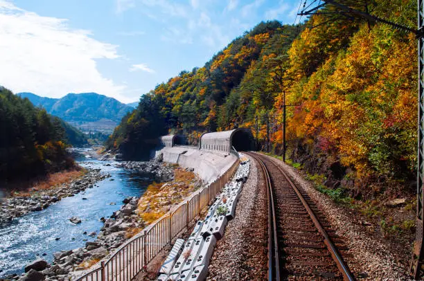 Gangwon-do, South Korea - Train tracks and tunnels along stream and autumn forest Baekdudaegan Mountain Range Canyon, famous tourist train route for autumn & winter between Buncheon - Cheoram stations.