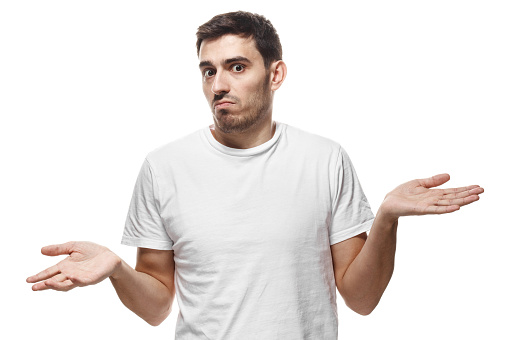 Horizontal picture of young European man in white blank T-shirt isolated on white background spreading his arms at loss in gesture of confusion or perplexity as if unable to give answer or advice