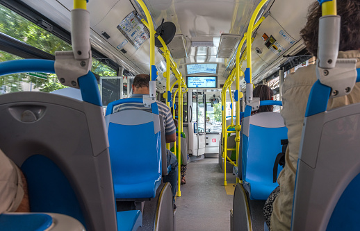 Madrid, Spain - July 27, 2018: Group of people traveling inside a modern public bus through Madrid. The public transportation system of Madrid has a modern fleet of buses with air conditioning and free Wi-Fi connection for passengers.