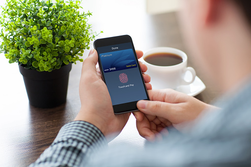 man hands holding phone with debit card touch and pay on screen in cafe