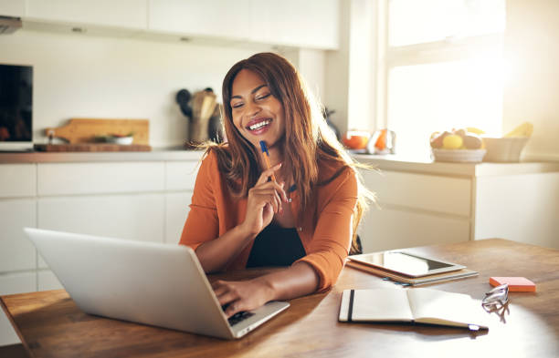 istock Smiling woman working online at her kitchen table at home 1019424026