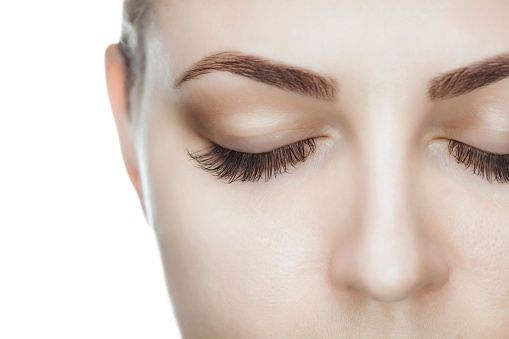 Beautiful Woman with long lashes in a beauty salon. Eyelash extension procedure.
