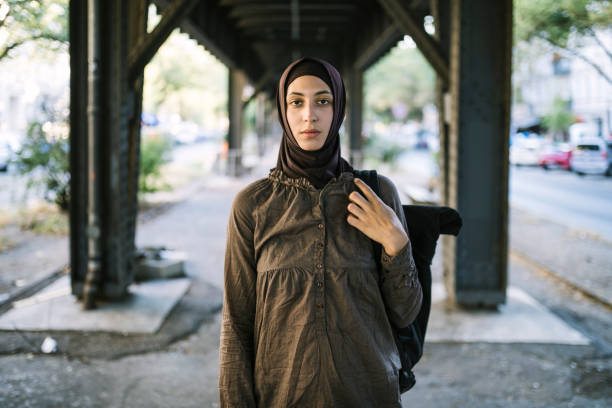 Portrait of a middle eastern woman looking at the camera taken under a bridge.