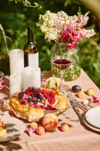 istock candles, wine and berries pie on table in garden 1019433772