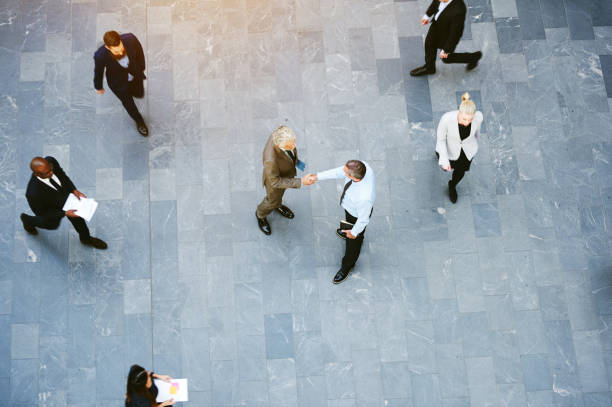 istock Businessmen shaking hands in crowded office hall 1019437930