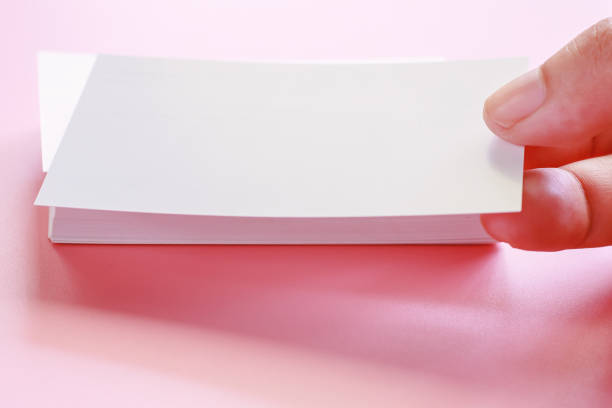 istock Hand holding blank business cards on pink background 1019440566