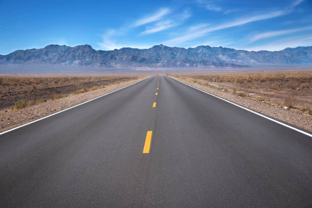 A Long Straight Empty Road An empty desert road in Death Valley National Park, California, United States of America. middle of the road stock pictures, royalty-free photos & images