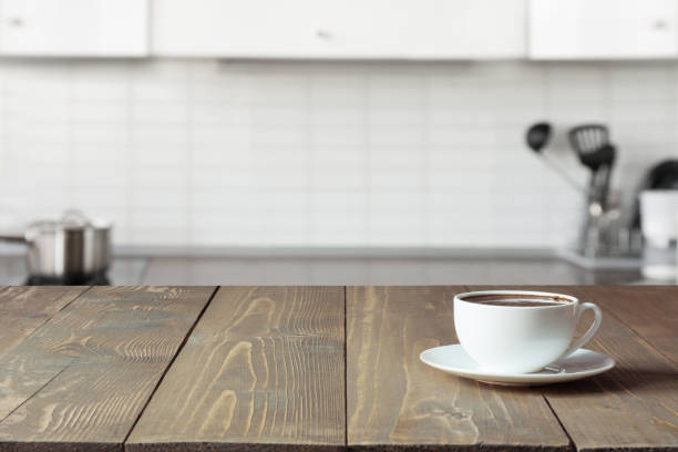 istock Cup of coffee on wooden board. Blurred kitchen as background. 1019452546