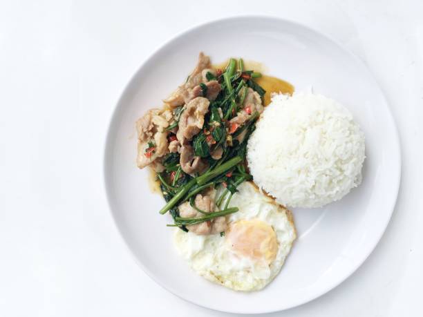 revuelva frito espinacas de agua con harina, huevo frito, estilo tailandés con arroz en plato blanco sobre fondo blanco. comida de estilo tailandés. - jangling fotografías e imágenes de stock