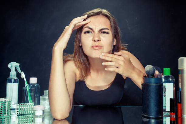istock Unsatisfied young woman looking at her self in mirror on black background 1019473692