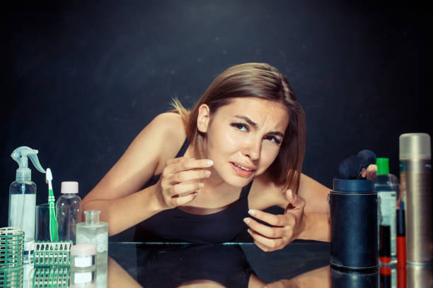 istock Unsatisfied young woman looking at her self in mirror on black background 1019473828
