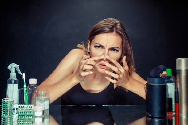 istock Unsatisfied young woman looking at her self in mirror on black background 1019474068