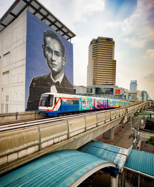 Bangkok Thailand Sky train passing in front of the King Bhumibol murale and Siam Discovery center Bangkok Thailand Sky train passing in front of the King Bhumibol murale and Siam Discovery center thailand king stock pictures, royalty-free photos & images