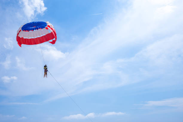 istock Three men are flying in the blue sky using a colorful parachute. 1019481120