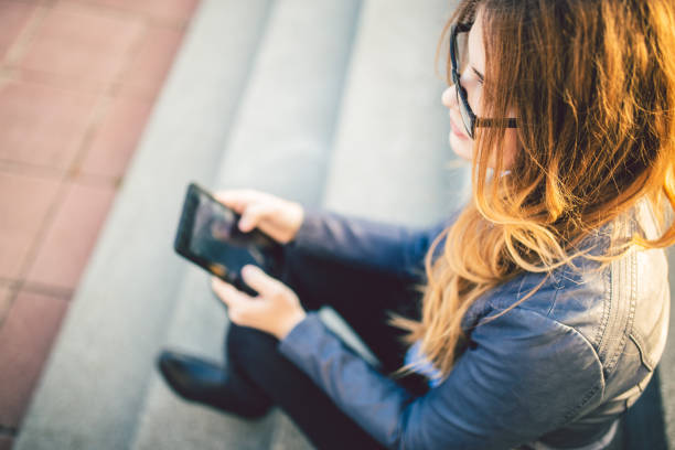 istock Girl sitting on the steps outdoor and using tablet. 1019489206