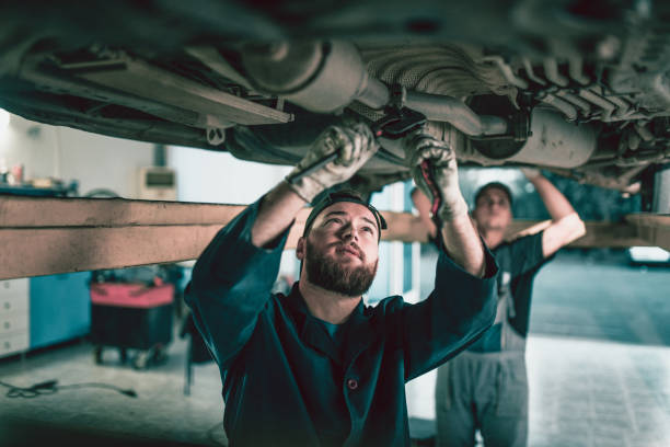 Team Of Mechanics Repairing Car Exhaust System Team Of Mechanics Repairing Car Exhaust System exhaust pipe photos stock pictures, royalty-free photos & images