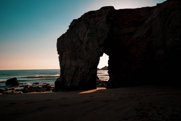 Sunset on a rock arch on the beach stock photo