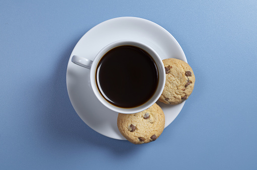Cup of coffee and cookies with chocolate on the blue table, top view