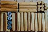 Wooden grooved dowels organized in different patterns n a clear container, with four steel dwel pins