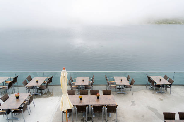 Terrace with tables on the lakeshore, fog, grimsel pass, Switzerland Garden terrace with tables and chairs in the fog, Grimsel Pass, Switzerland grimsel pass photos stock pictures, royalty-free photos & images