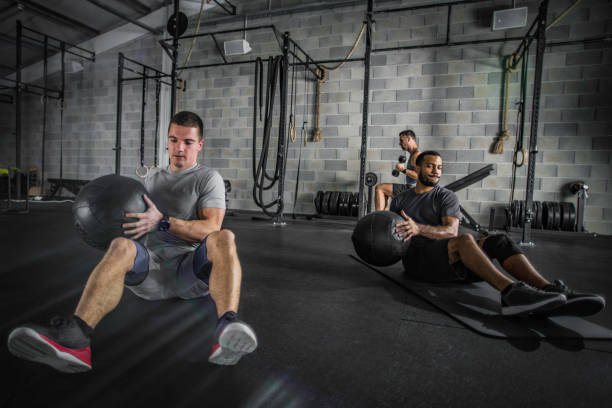 istock Two men doing crunches with medicine balls in the gym 1019531512