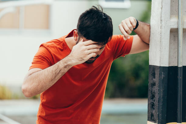 mann leidet unter schwindel mit mühe aufstehen und stützte sich auf wand - schwindelig stock-fotos und bilder