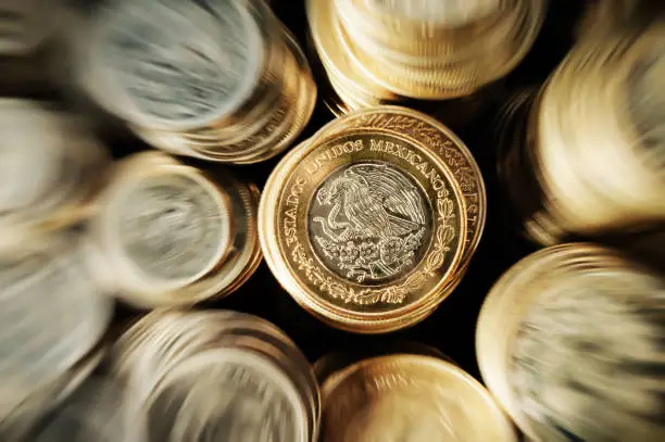 A Mexican peso coin stacked on the eagle face side