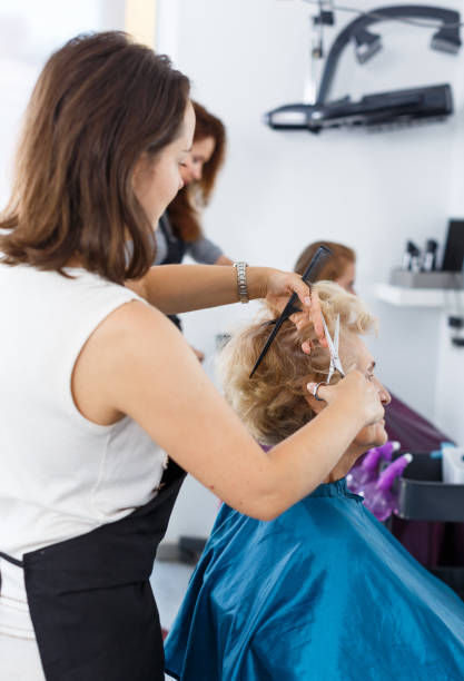 Senior lady getting haircutting by professional woman hairdresser in salon
